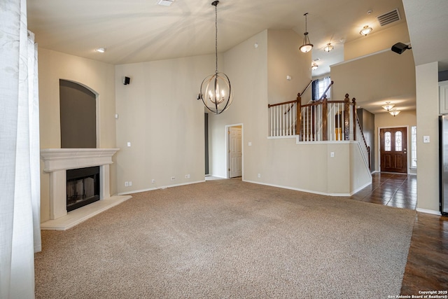 unfurnished living room with dark carpet, a chandelier, and high vaulted ceiling