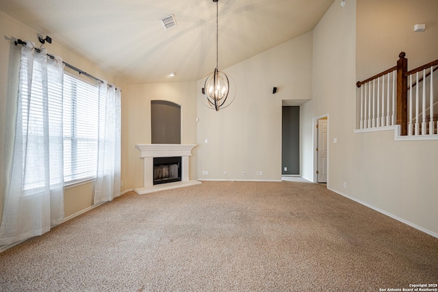 unfurnished living room with high vaulted ceiling, carpet floors, and a notable chandelier