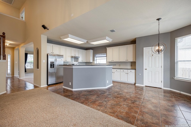 kitchen with pendant lighting, white cabinetry, a center island, stainless steel fridge with ice dispenser, and a chandelier