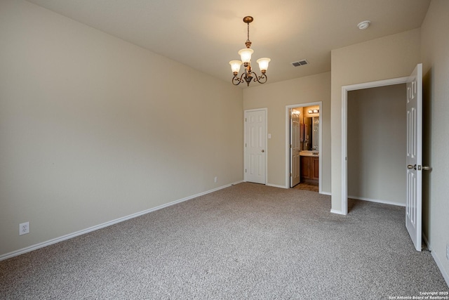 unfurnished bedroom with carpet flooring, an inviting chandelier, and ensuite bath