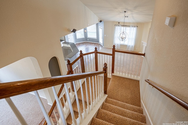 stairs featuring carpet flooring and a chandelier