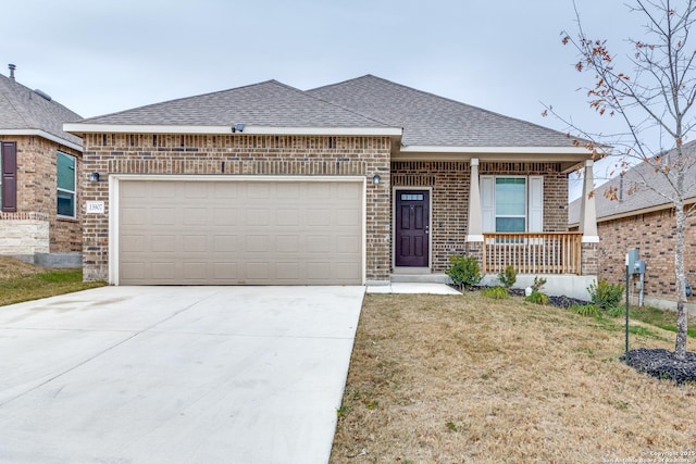 view of front of home with covered porch, a garage, and a front lawn