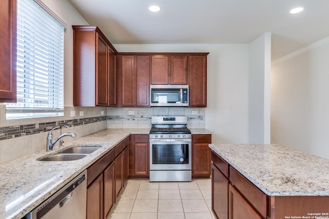 kitchen featuring light stone countertops, stainless steel appliances, tasteful backsplash, sink, and light tile patterned floors