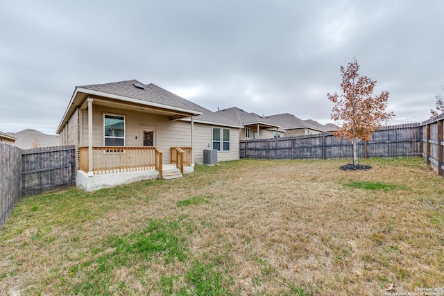 back of property with central air condition unit and a lawn