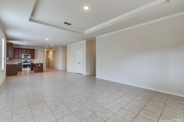 unfurnished living room featuring sink, ornamental molding, a raised ceiling, and light tile patterned flooring