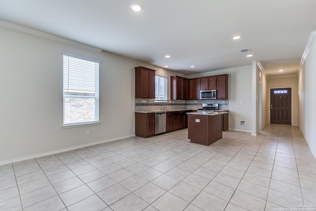 kitchen with light tile patterned floors, dark brown cabinetry, stainless steel appliances, and a center island