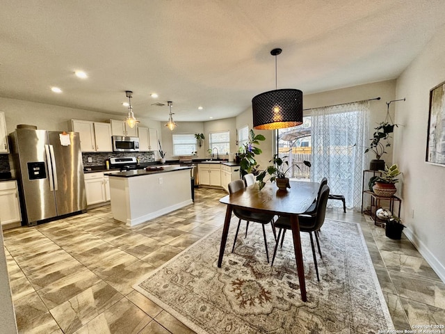 kitchen featuring appliances with stainless steel finishes, a wealth of natural light, pendant lighting, white cabinets, and sink