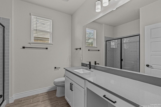 bathroom featuring toilet, a shower with door, and vanity