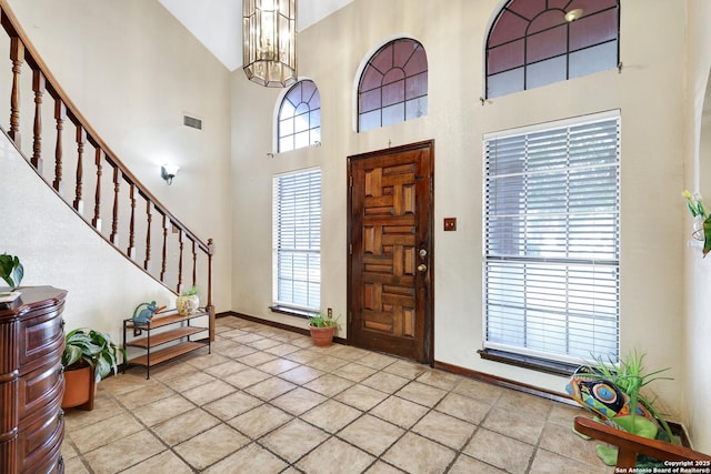 entrance foyer with a wealth of natural light, a notable chandelier, and a towering ceiling