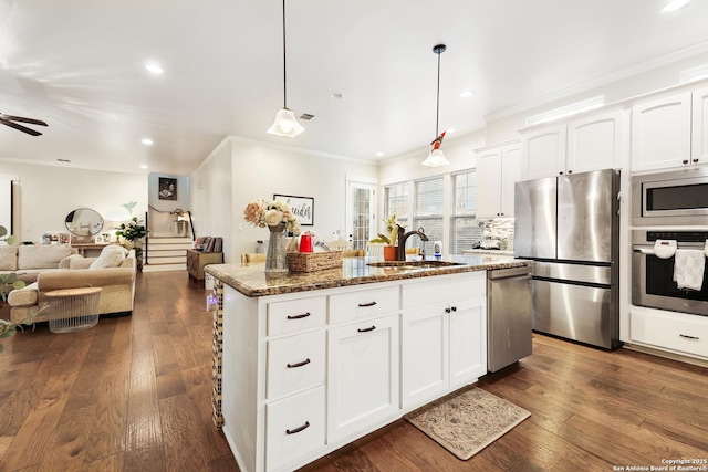 kitchen featuring an island with sink, stainless steel appliances, hanging light fixtures, white cabinets, and light stone counters