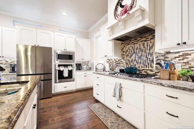 kitchen featuring exhaust hood, dark hardwood / wood-style floors, stainless steel appliances, white cabinets, and light stone counters