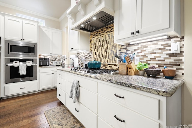 kitchen with extractor fan, stainless steel appliances, backsplash, light stone countertops, and white cabinets