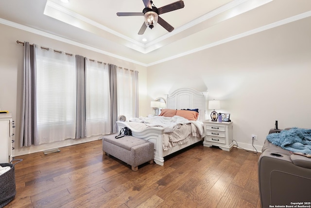 bedroom featuring dark wood-type flooring, ceiling fan, crown molding, and a raised ceiling