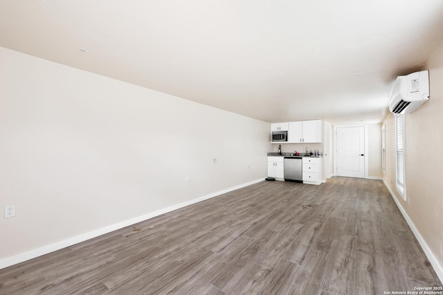 unfurnished living room with light hardwood / wood-style flooring and a wall mounted air conditioner