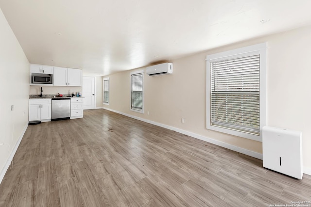 unfurnished living room with light hardwood / wood-style floors and a wall unit AC