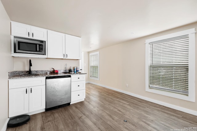 kitchen with dishwasher, stone counters, light hardwood / wood-style floors, sink, and white cabinets