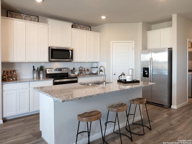 kitchen featuring white cabinets, appliances with stainless steel finishes, dark wood-type flooring, sink, and a kitchen island with sink