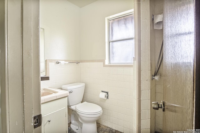 bathroom with tile walls, toilet, and vanity