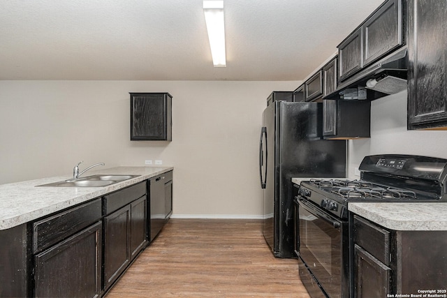 kitchen with light hardwood / wood-style floors, kitchen peninsula, black range with gas cooktop, stainless steel dishwasher, and sink