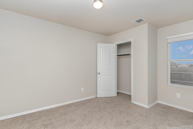 unfurnished bedroom featuring light carpet and a closet