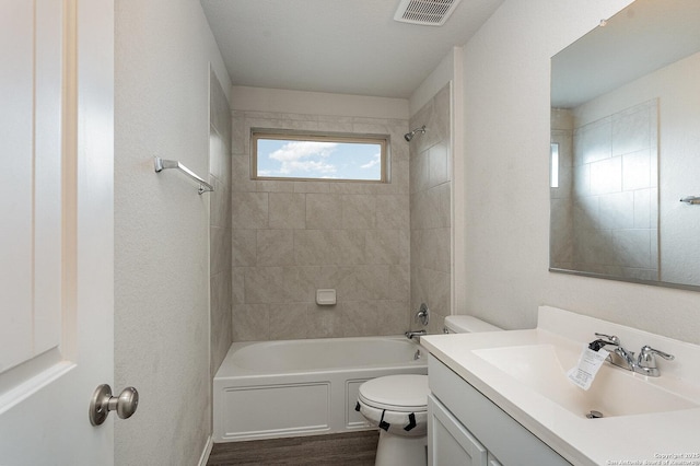 full bathroom with toilet, tiled shower / bath combo, vanity, and hardwood / wood-style floors