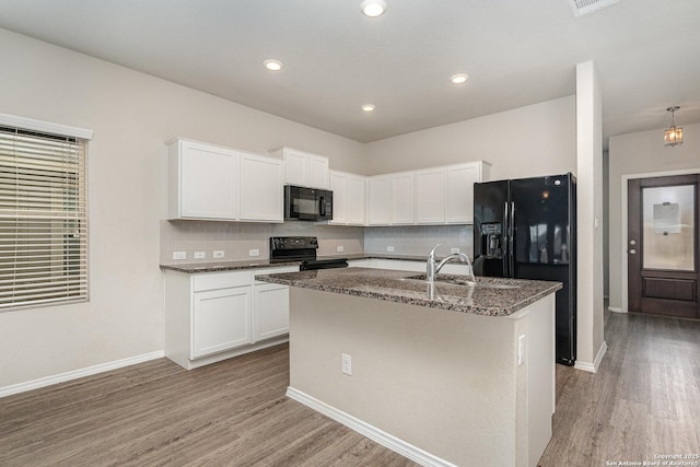 kitchen featuring white cabinetry, light hardwood / wood-style floors, an island with sink, and black appliances