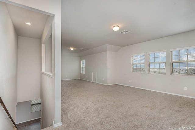 unfurnished room featuring carpet and vaulted ceiling