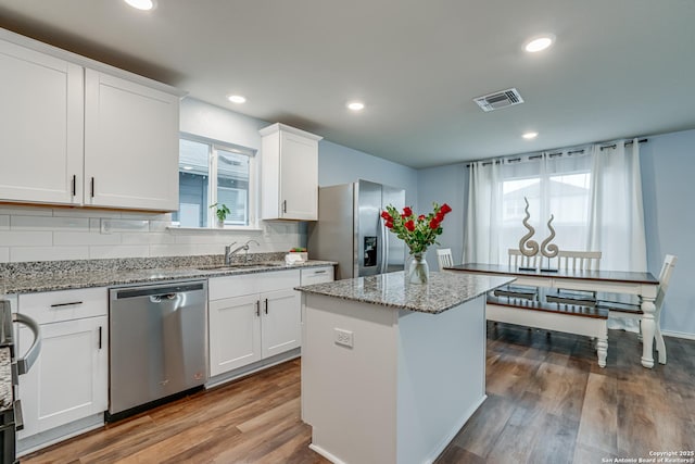 kitchen with appliances with stainless steel finishes, a center island, white cabinets, and sink