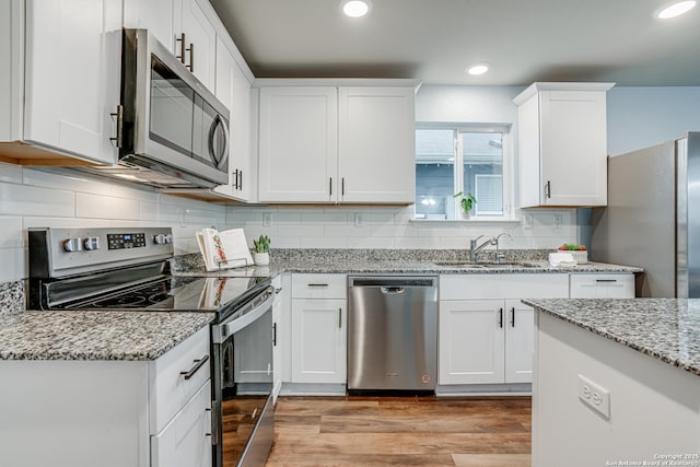 kitchen with sink, white cabinets, appliances with stainless steel finishes, and light wood-type flooring