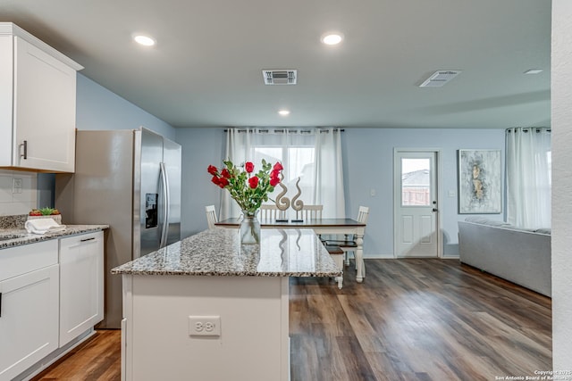 kitchen with dark hardwood / wood-style floors, a center island, white cabinets, stainless steel fridge, and light stone counters