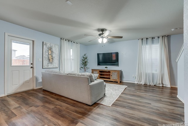 living room featuring ceiling fan and dark wood-type flooring