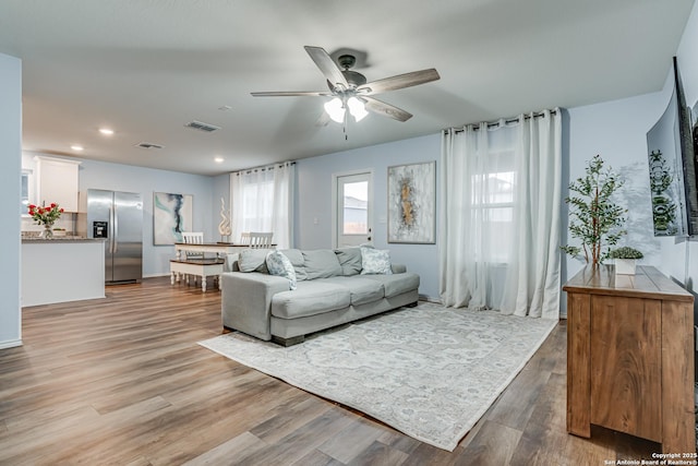 living room with light hardwood / wood-style floors and ceiling fan