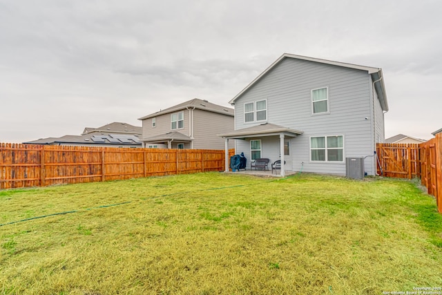 rear view of property featuring a patio area, central AC unit, and a lawn