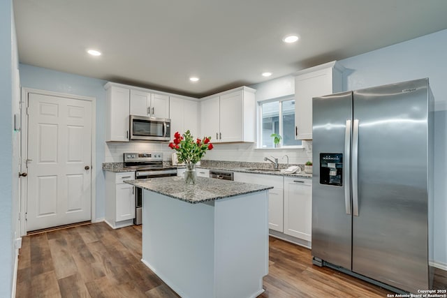 kitchen with white cabinets, light stone countertops, sink, and stainless steel appliances