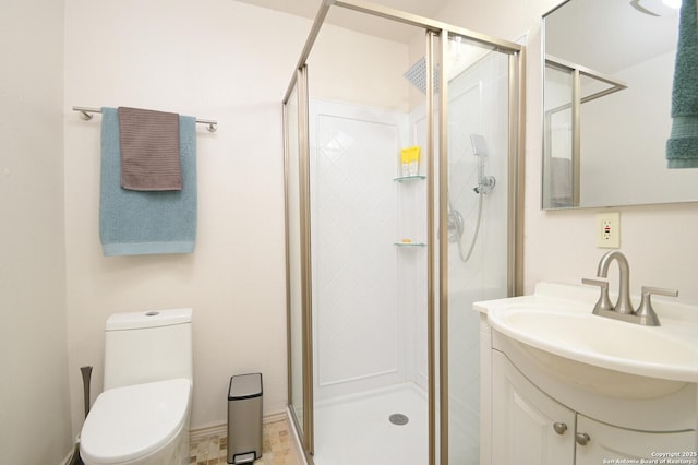 bathroom with toilet, vanity, and a shower with shower door