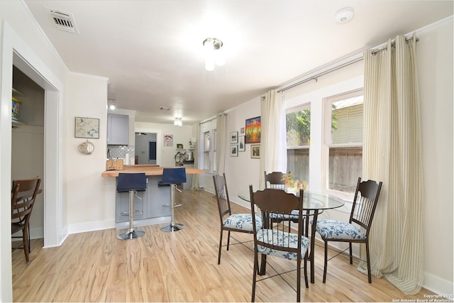 dining room with crown molding and light hardwood / wood-style floors