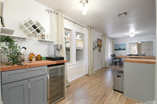 kitchen featuring wooden counters, gray cabinets, tasteful backsplash, light wood-type flooring, and wine cooler