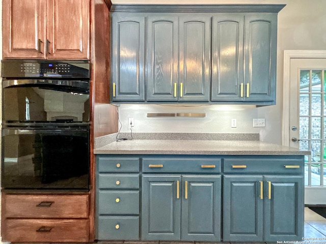 kitchen with black double oven and blue cabinetry