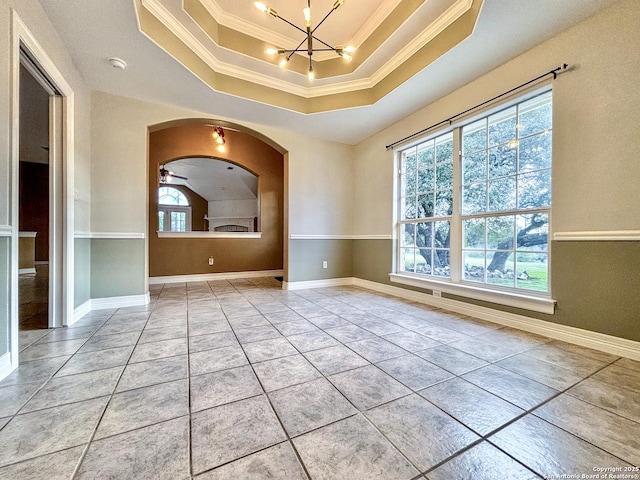 unfurnished room featuring ceiling fan with notable chandelier, light tile patterned flooring, a tray ceiling, and ornamental molding