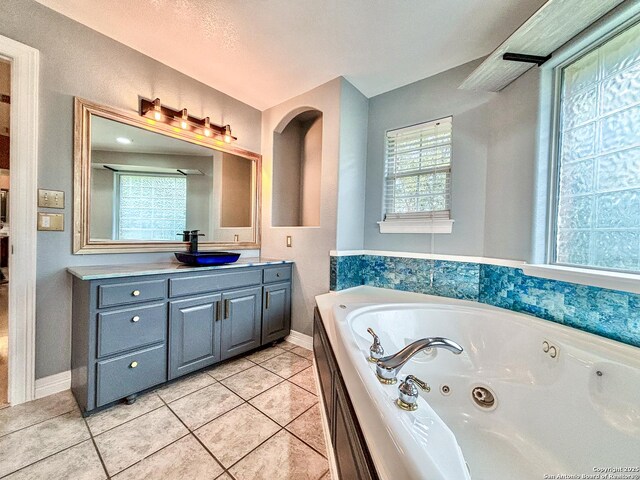 bathroom with a tub, a textured ceiling, vanity, and tile patterned flooring