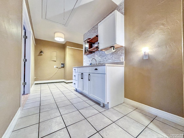 kitchen with light tile patterned floors, decorative backsplash, sink, and white cabinetry