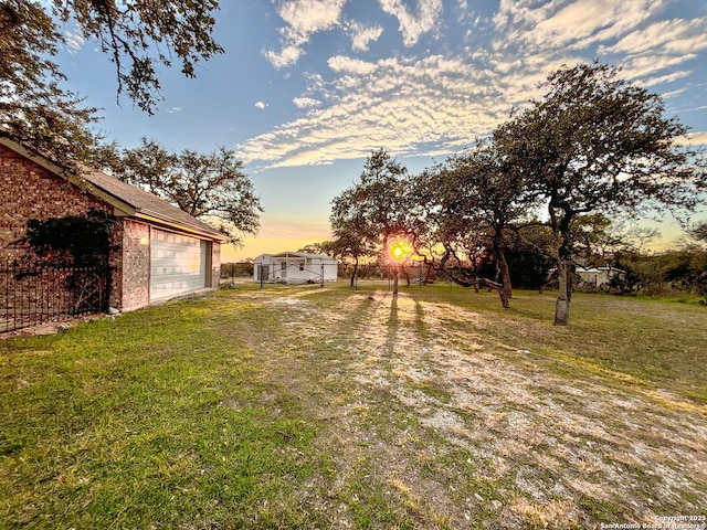 yard at dusk featuring a garage and an outdoor structure