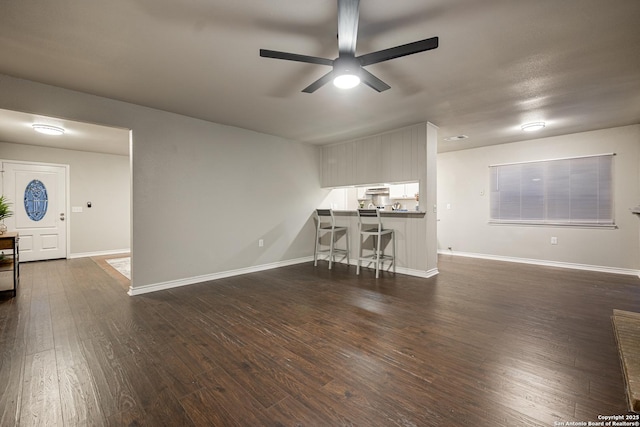 unfurnished living room featuring ceiling fan and dark wood-type flooring