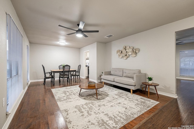 living room featuring ceiling fan and dark hardwood / wood-style floors