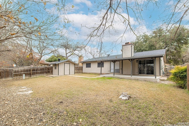 rear view of property with a yard, a patio, and a storage unit