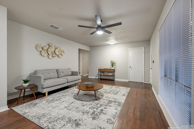 living room featuring ceiling fan and dark wood-type flooring