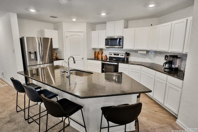 kitchen featuring white cabinets, appliances with stainless steel finishes, sink, a kitchen breakfast bar, and a kitchen island with sink