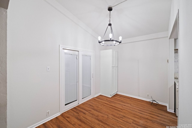 unfurnished dining area featuring hardwood / wood-style flooring, lofted ceiling, and a notable chandelier