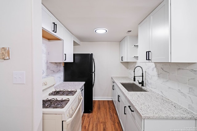 kitchen featuring white cabinets, backsplash, sink, and white gas stove