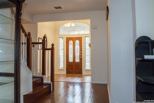 foyer featuring wood-type flooring, a wealth of natural light, and an inviting chandelier